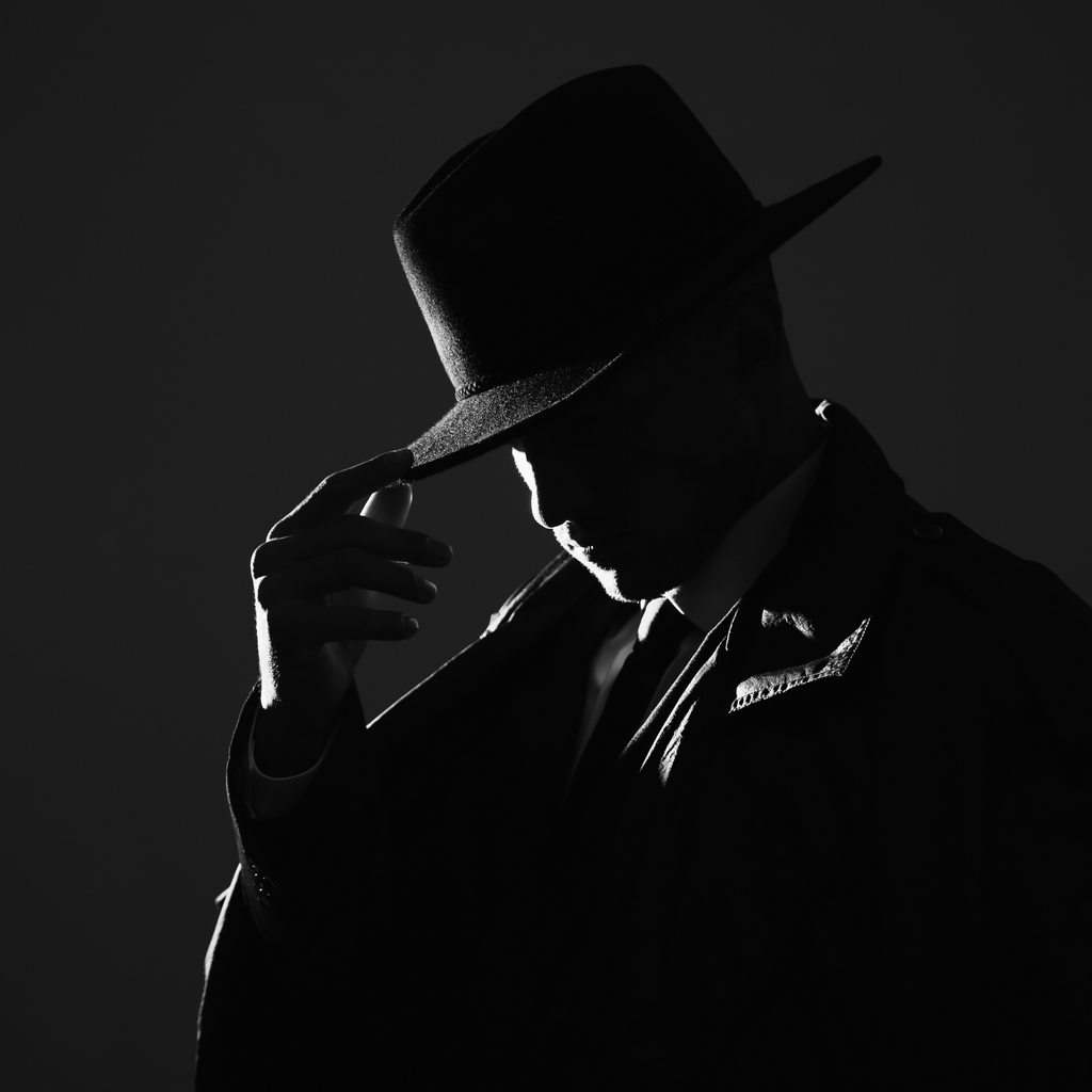 A silhouetted man in a trench coat tips his hat.